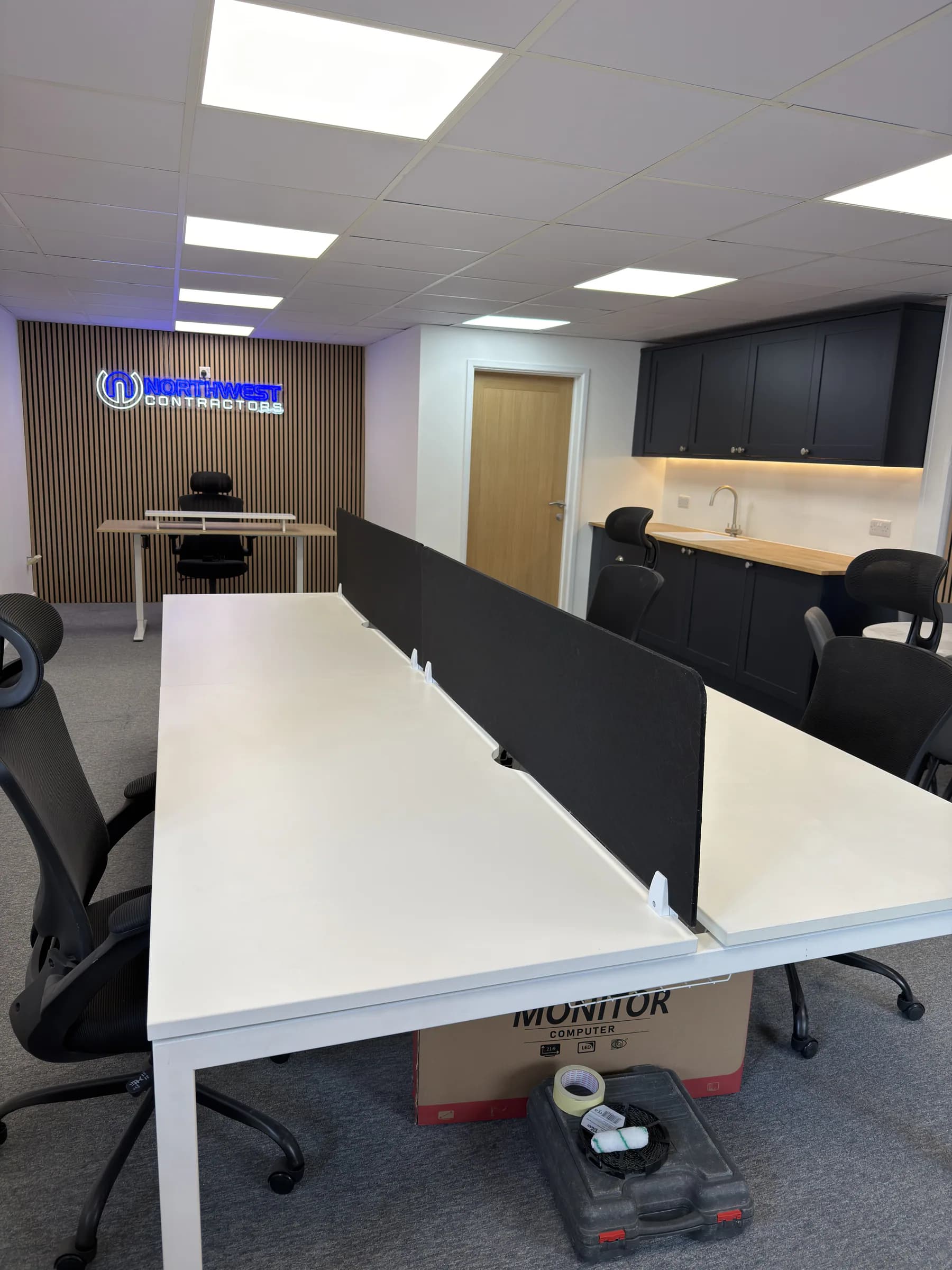 Completed commercial office fit-out in Saltney with workstations, a kitchenette and a timber-slat feature wall