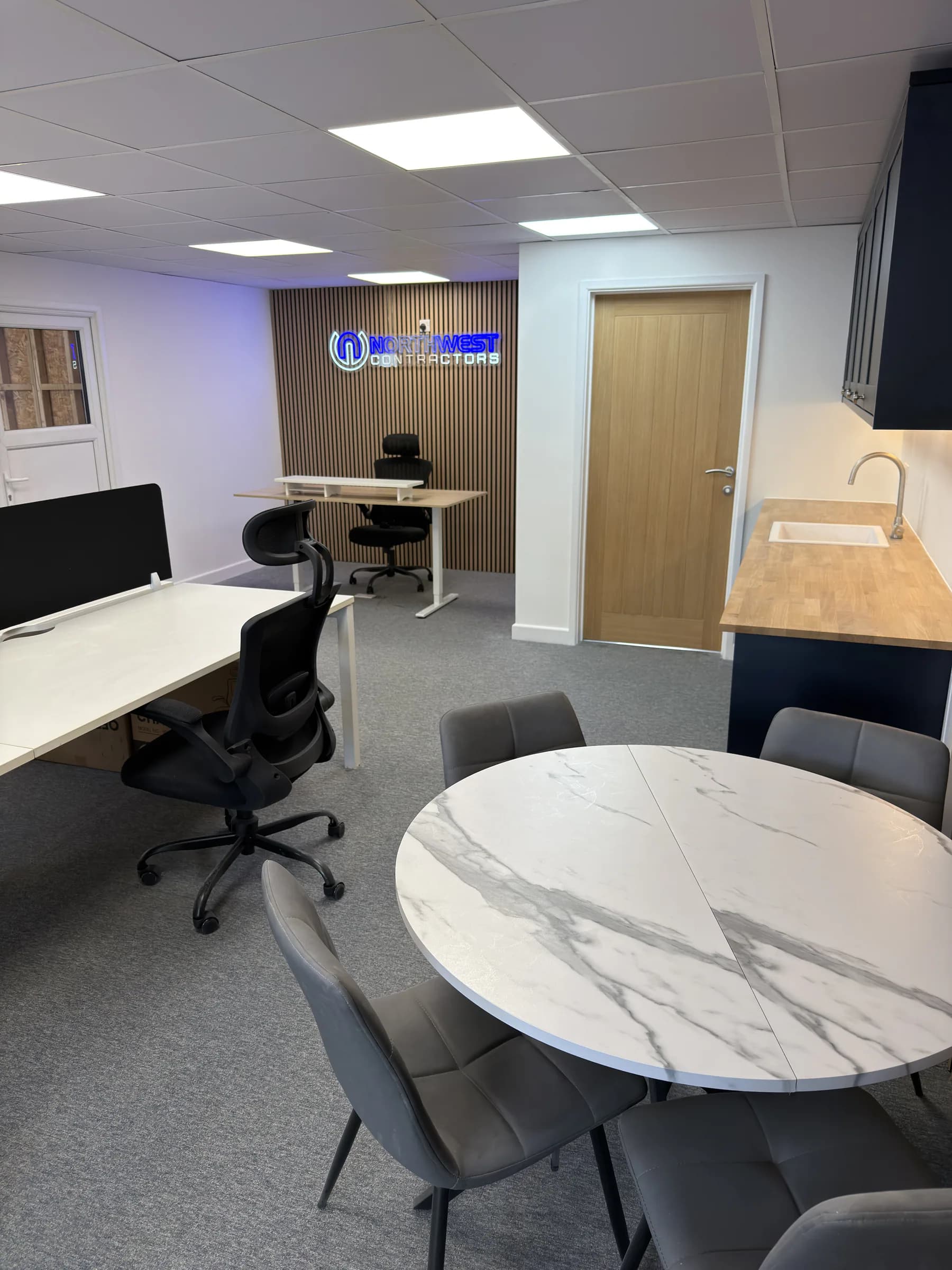 Completed Saltney office fit-out with workstations, a meeting table, fitted kitchenette and timber-slat feature wall