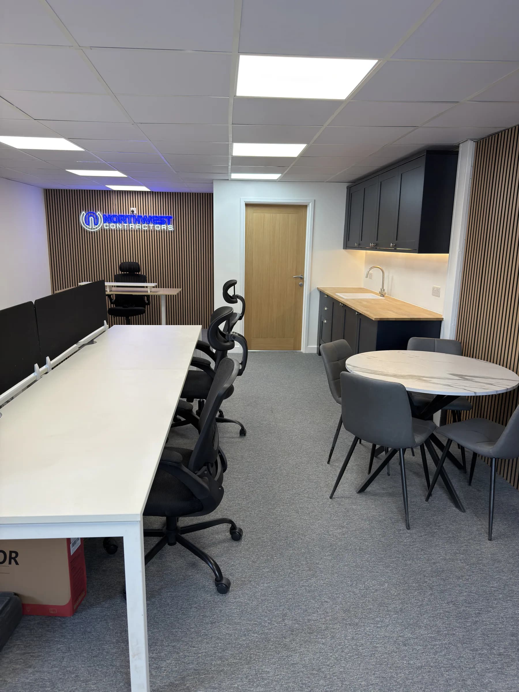Completed office showing workstations, a meeting area and a branded timber-slat wall