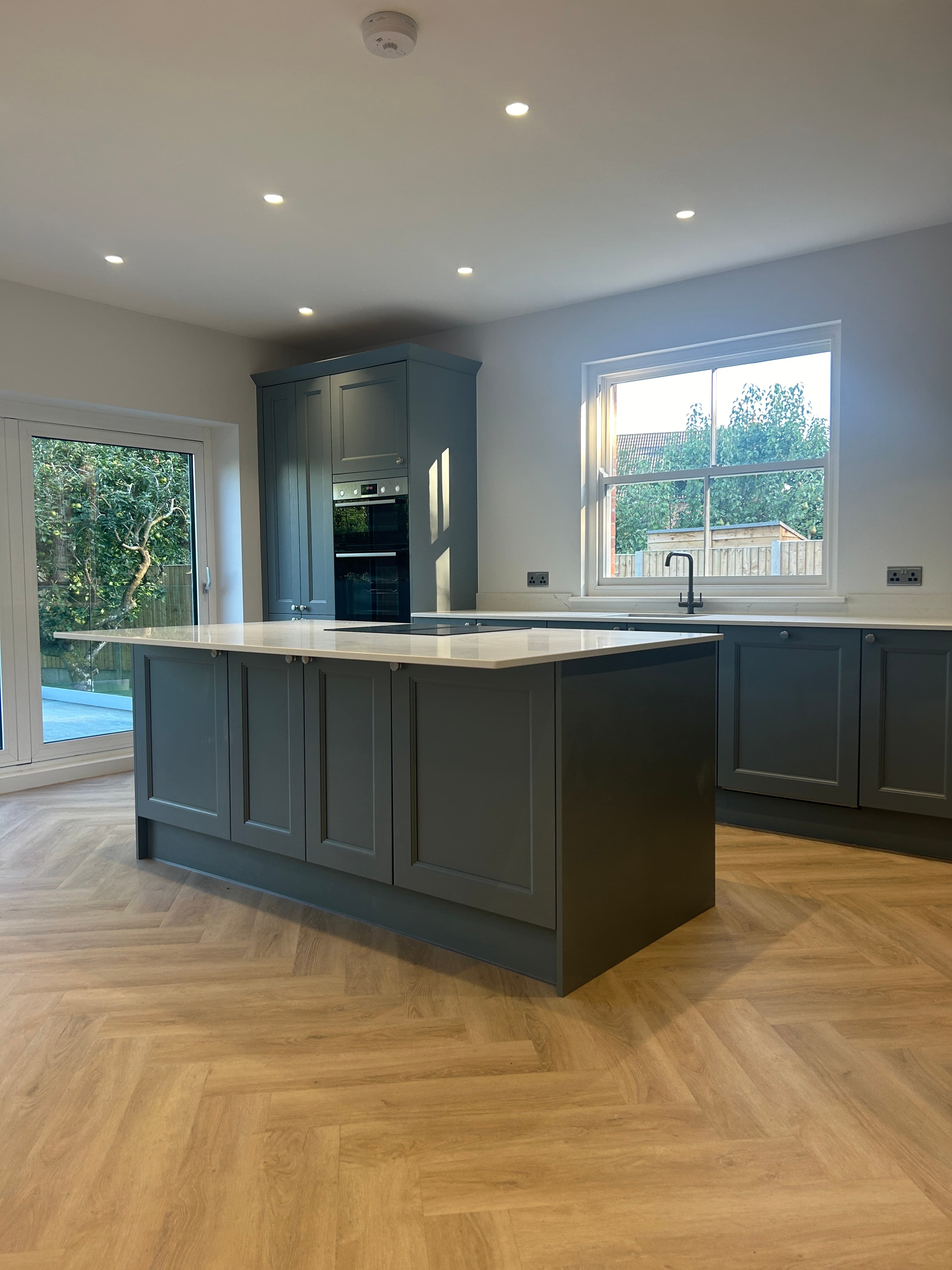 Kitchen island and tall grey shaker units in a finished renovation